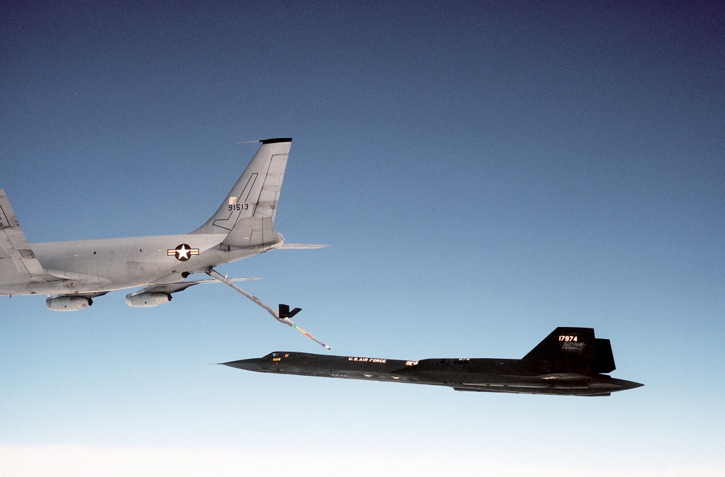 A left side view of an SR-71 aircraft moving toward a KC-135 Stratotanker aircraft for inflight refueling.  The SR-71 is from the 9th Strategic Reconnaissance Wing.